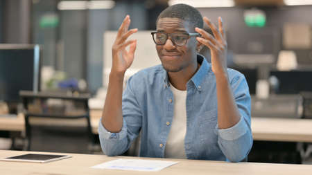 Upset Young African Man Worried While Sitting in Office