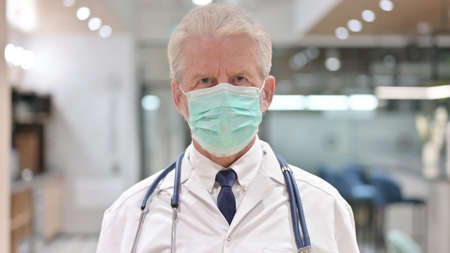 Portrait of Old Doctor with Face Mask Looking at the Camera