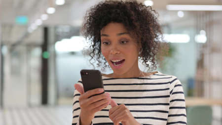 Portrait of African Woman Celebrating Success on Smartphone