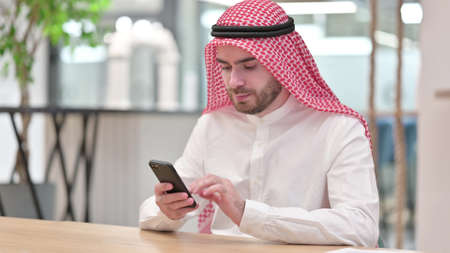 Arab Businessman Browsing Internet on Smartphone in Office