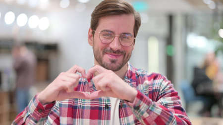 Portrait of Young Man Showing Heart Shape by Handの写真素材
