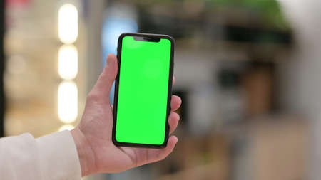 Hand Holding Smartphone with Green Screenの写真素材