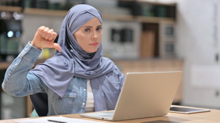 Arab Woman with Laptop showing Thumbs Downの写真素材