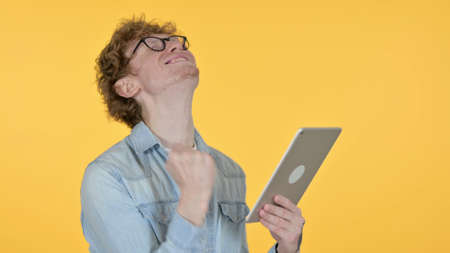 Redhead Man Celebrating on Tablet, Yellow Background