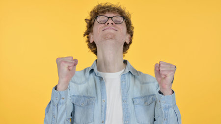 Excited Redhead Man Celebrating, Yellow Backgroundの写真素材
