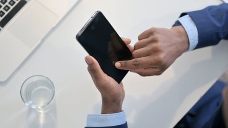 Hands of African Businessman using Smartphone, Top Viewの写真素材