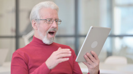 Successful Old Man Celebrating on Tabletの写真素材