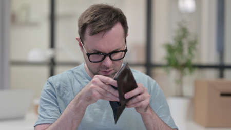 Young Man Checking Empty Wallet at Workの写真素材
