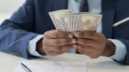 Hands of African Businessman Counting Dollars, Close Upの写真素材