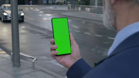 Old Businessman using Smartphone with Green Screen, Outdoorの写真素材