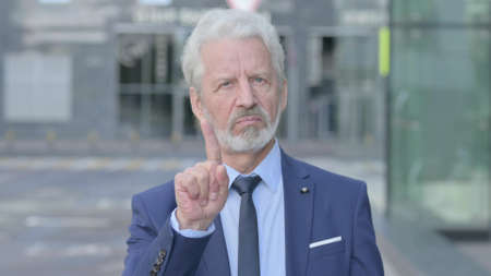 Outdoor Old Businessman showing No Sign by Finger Signの写真素材