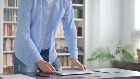 Man Coming Back and Opening Laptop in Officeの写真素材
