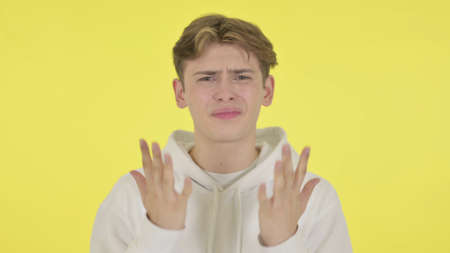 Disappointed Young Man Reacting Loss on Yellow Background