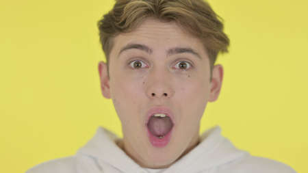 Close Up of Shocked Young Man, Yellow Backgroundの写真素材