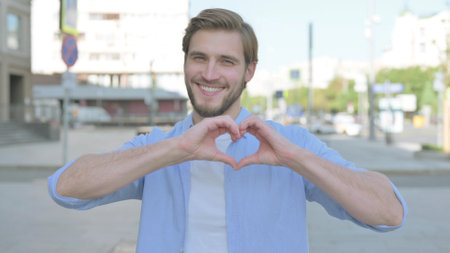 Loving Man showing Heart Shape by Hands Outdoorの写真素材
