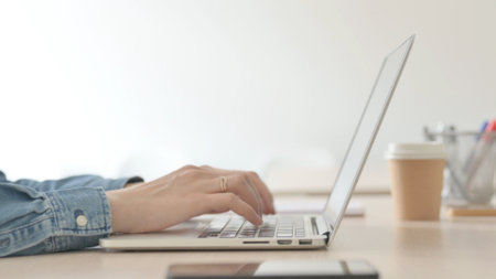 Close Up of Female Hands Typing on Laptop, Side Viewの写真素材
