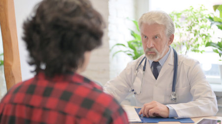The Old Doctor Talking with Patient in Clinicの写真素材