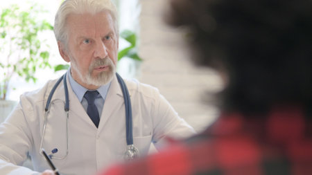 The Close Up of Old Doctor Talking with Patient in Clinicの写真素材