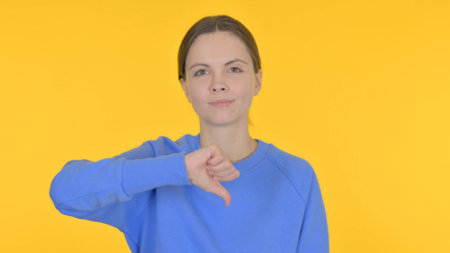 Thumbs Down by Casual Woman on Yellow Background
