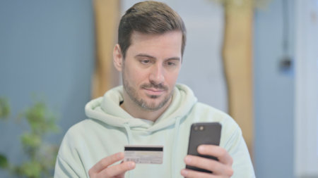 Young Adult Man Shopping Online on Smartphoneの写真素材