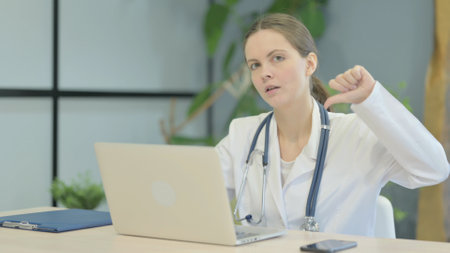 Thumbs Down by Young Female Doctor Working on Laptopの写真素材