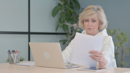 Reading Document by Mature Adult and Working on Laptopの写真素材
