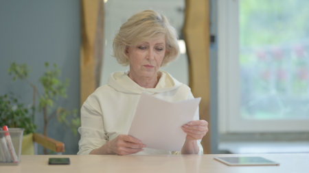 Mature Adult Woman Reading Documents at Work, Paperworkの写真素材