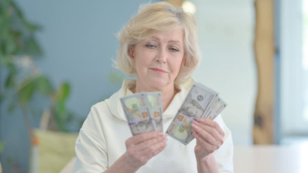Mature Woman Counting Dollars at Home, Money Handlingの写真素材