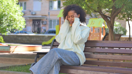 Casual African Woman Sitting Outdoor with Headacheの写真素材