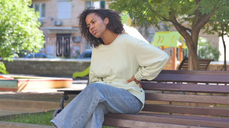 Casual African Woman Sitting Outdoor with Back Pain
