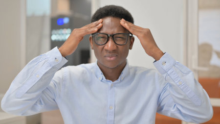 Portrait of African Businessman with Headache in Officeの写真素材
