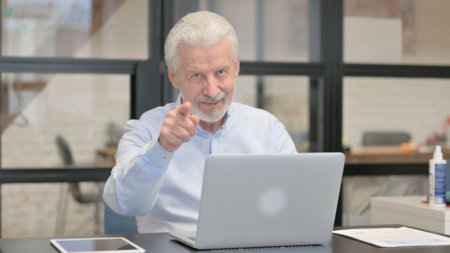 Old Businessman Pointing at Camera in Office