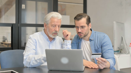 Mature Man Showing Credit Card to His Colleague in Office