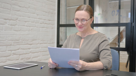 Senior Old Woman Celebrating while Reading Documentsの写真素材