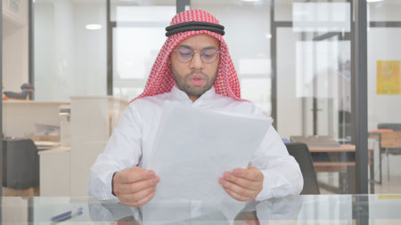 Young Muslim Man Reading Documents at Workの写真素材