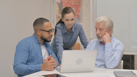 Mixed Race Teammates Working on Laptopの写真素材