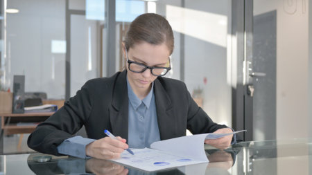 Young Businesswoman Doing Paperwork in Officeの写真素材