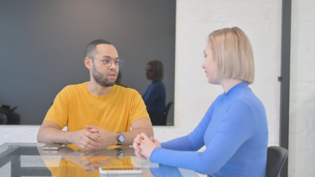 Mixed Race Creative Man Talking with Blonde Womanの写真素材