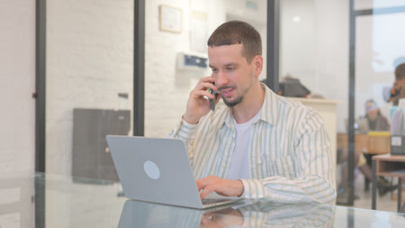 Creative Young Man Talking on Phone at Workの写真素材