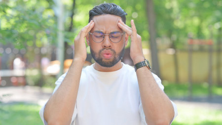 Young Man with Migraine Outdoor in Parkの写真素材