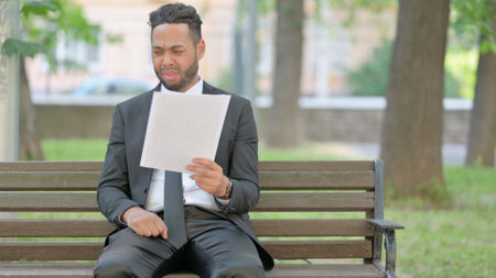 Businessman Shocked while Reading Documents Outdoor on Benchの写真素材