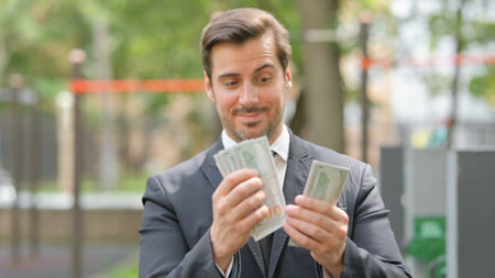 Portrait of Young Businessman Counting Money Outdoorの写真素材
