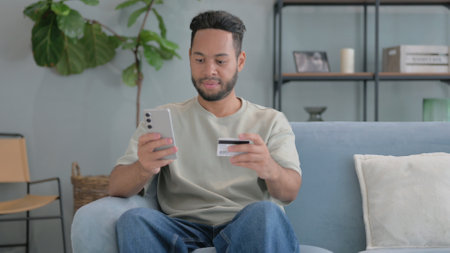 Happy Hispanic Man Enjoying Online Banking at Home