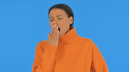 Yawning Casual African Woman on Blue Background, Portraitの写真素材