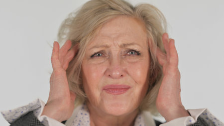Portrait of senior woman suffering from headache on white background. Focus on foreground.の写真素材