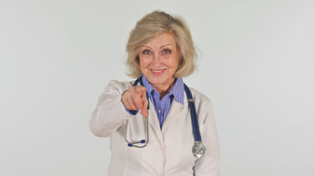 Portrait of senior woman doctor with stethoscope pointing at cameraの写真素材