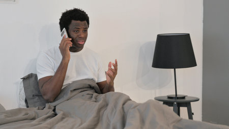 Angry African Man Talking on Phone while in Bed