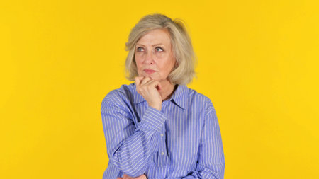 Old Woman Brainstorming New Idea on Yellow Background, Portraitの写真素材