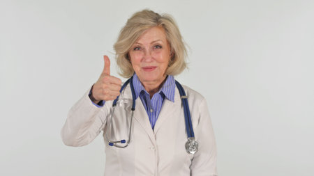 Portrait of Senior Female Doctor with Thumbs Up on White Backgroundの写真素材