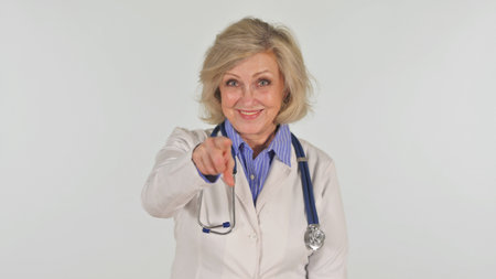 Portrait of Senior Female Doctor Pointing at Camera on White Backgroundの写真素材